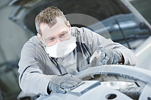 Repair man worker sanding automobile car body in garage