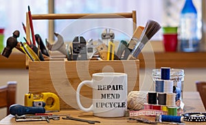 Repair Mend upcycle on a mug surrounded by repair tools, consumer activism to repair