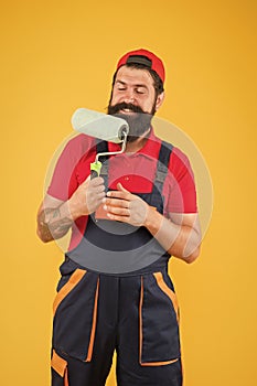 Repair paintng tool. cheerful bearded man worker with roller tool. hipster artist decorator yellow wall. erector photo