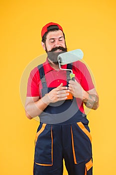 Repair paintng tool. cheerful bearded man worker with roller tool. hipster artist decorator yellow wall. erector