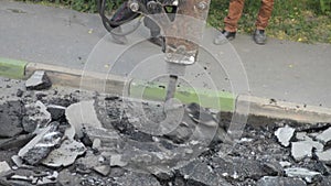 Repair section of the road surface. Hydraulic hammer breaker on excavator destroying asphalt layer near the curb stone.