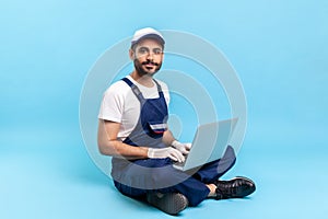 Repair service, online support. Portrait of happy professional handyman in blue workwear and protective gloves