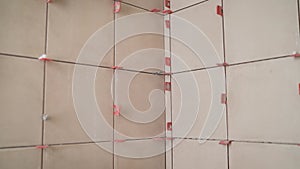 Repair of tiles in the bathroom. Close up of tiles fixing wall tiles with spacers at home, renovation work