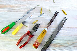 Repair tools on a wooden light background: file, pliers, pliers, screwdriver, screws, bolts