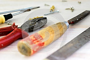 Repair tools on a wooden light background: file, pliers, pliers, screwdriver, screws, bolts