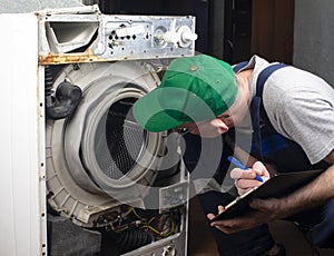 Repair of washing machines. A technician examines an old broken washing machine and records