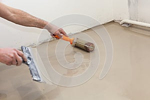 Repair work. Pouring floors in the room. Fill screed floor repair and furnish. Worker align cement with roller