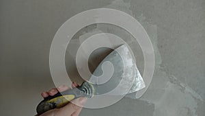 Repair work on puttying a plasterboard wall with an iron spatula