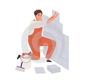 Repair worker laying ceramic wall tile. Professional tiler in uniform working. Repairman in overalls tiling at home