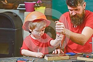 Repair and workshop concept. Boy, child busy in protective helmet learning to use screwdriver with dad. Father, parent