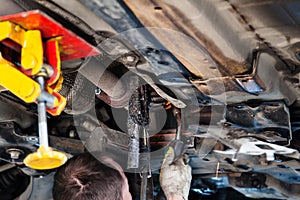Repairer welds silencer on car by argon welding