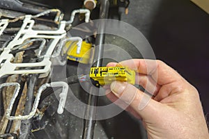 Repairing automotive electrical wiring. An auto electrician holds a connector of the car& x27;s electrical wiring in