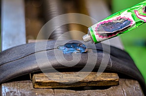 Repairing bicycle tube In workshop. Close up image of glue to repair inner tube of bicycle wheel. The mechanic does his job