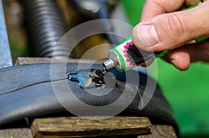 Repairing bicycle tube In workshop. Close up image of glue to repair inner tube of bicycle wheel. The mechanic does his job