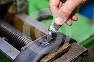 Repairing bicycle tube In workshop. Close up image of glue to repair inner tube of bicycle wheel. The mechanic does his job