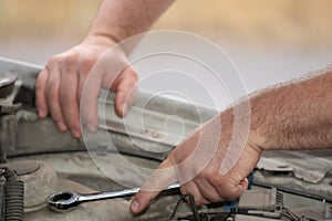 repairing a car, the hands of a mechanic tigheten a nut with a metal wrench