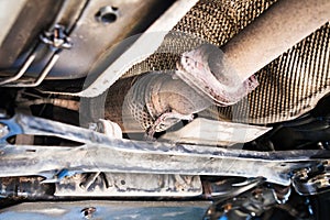 Bottom view of broken corrugation muffler on car photo