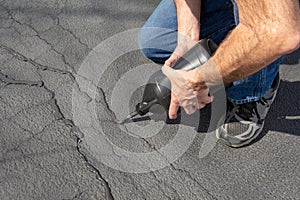 Repairing cracks in driveway with asphalt crack filler