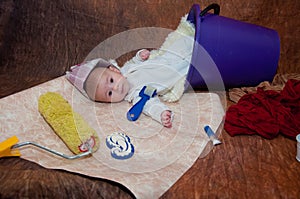 Repairing. Little child in hat mae of newspaper, laying in bucket near different instruments, wallpaper