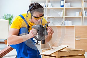 Repairman carpenter cutting sawing a wooden board with an electr