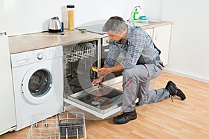 Repairman Checking Dishwasher With Digital Multimeter