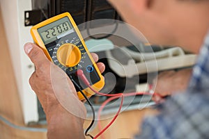 Repairman Checking Fridge With Digital Multimeter photo