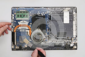 Repairman cleaning a disassembled laptop on a white background. . Dusty computer