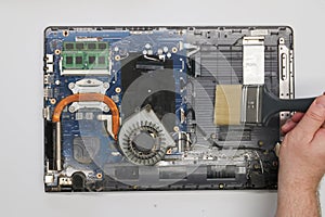 Repairman cleaning a disassembled laptop on a white background. Isolated. Dusty computer