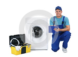 Repairman with clipboard and toolbox near washing machine on background