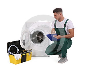 Repairman with clipboard and toolbox near washing machine on background