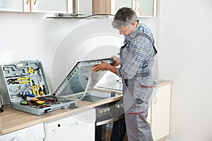 Repairman Examining Stove In Kitchen