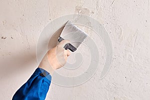 Repairman is finishing wall at home with putty and work tool