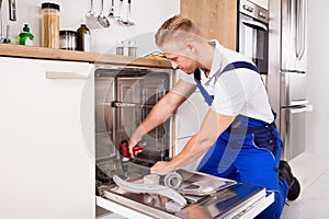 Repairman Fixing Dishwasher In Kitchen