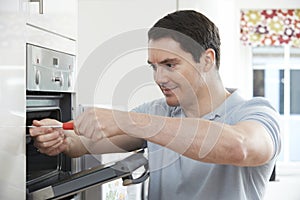 Repairman Fixing Domestic Oven In Kitchen