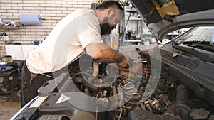 Repairman fixing engine of car using wrench at workshop or service. Professional auto mechanic works under hood of