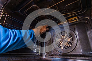 Repairman fixing the motor fan inside in the oven