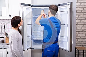 Repairman Fixing Refrigerator With Screwdriver photo