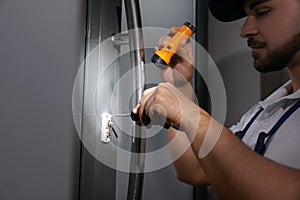 Repairman with flashlight fixing door lock