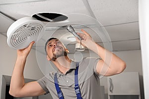 Repairman with flashlight fixing ventilation system