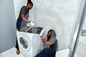 Repairman on floor in bathroom fixing washing machine