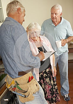 Repairman Giving Senior Couple Estimate For Repair