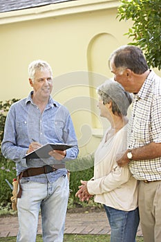 Repairman Giving Senior Couple Estimate For Roof Repair