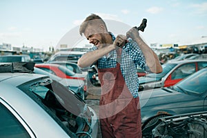 Repairman hits the glass with hammer, car junkyard