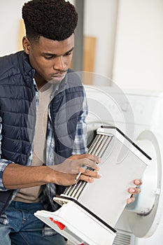 repairman holding condenser from tumble dryer