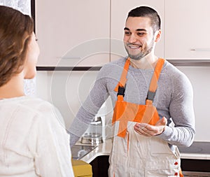 Repairman and housewife at kitchen