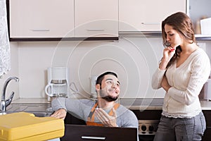 Repairman and housewife at kitchen