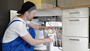 Repairman installing water filter cartridges in a kitchen. Installation of reverse osmosis water purification system