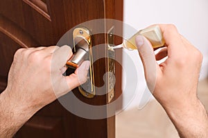 Repairman lubricating door lock indoors, closeup view