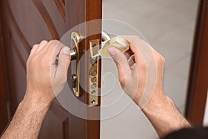 Repairman lubricating door lock indoors, closeup view