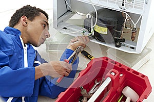 Repairman makes refrigerator appliance troubleshooting and maintenance